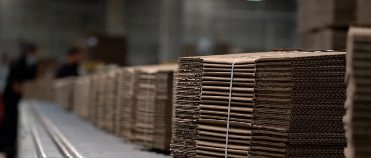 Planchas de cartón corrugado apiladas sobre una línea de producción.